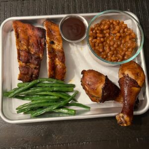 BBQ ribs and smoked chicken legs with green beans and baked beans from Tutta’s BBQ combo meal.